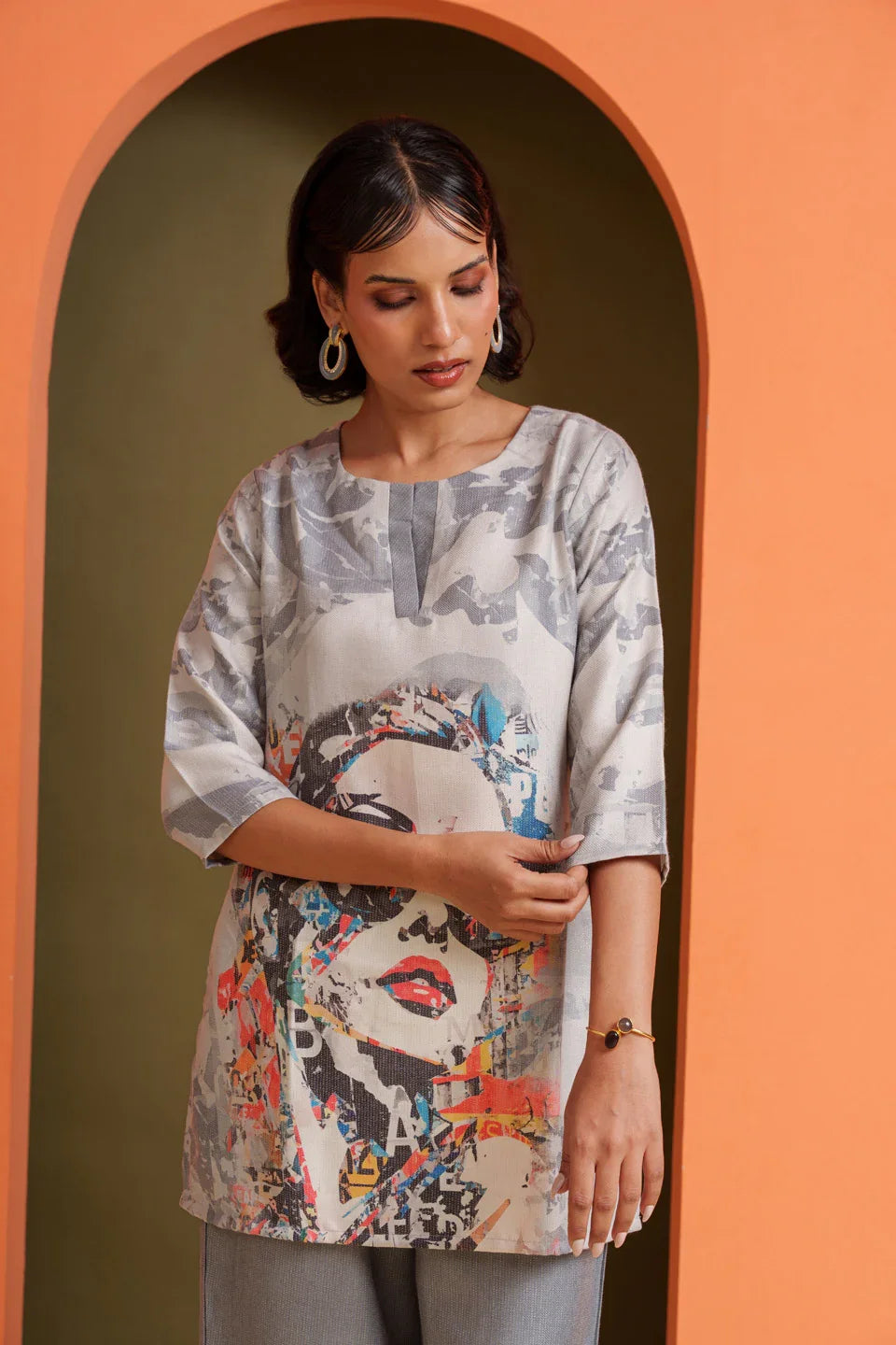 Woman in artistic print tunic with abstract face design, soft viscose fabric, modern designer wear